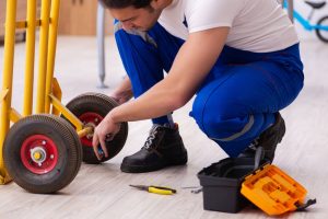 Young repairman repairing trolley indoors