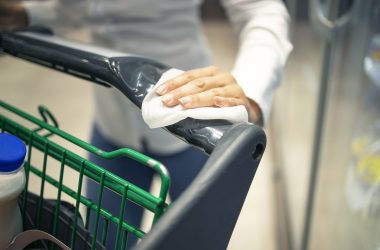 Woman disinfecting shopping cart with sanitizer before use due to corona virus pandemic. Woman disinfecting shopping cart with sanitizer before use due to corona virus pandemic.